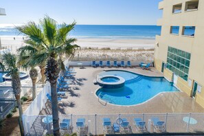 A pool area with lounge chairs and a view of the beach. - Crystal Shores West Beachfront 2 Bed. Indoor/Outdoor Pool. Free Daily Activities (Gulf Shores)