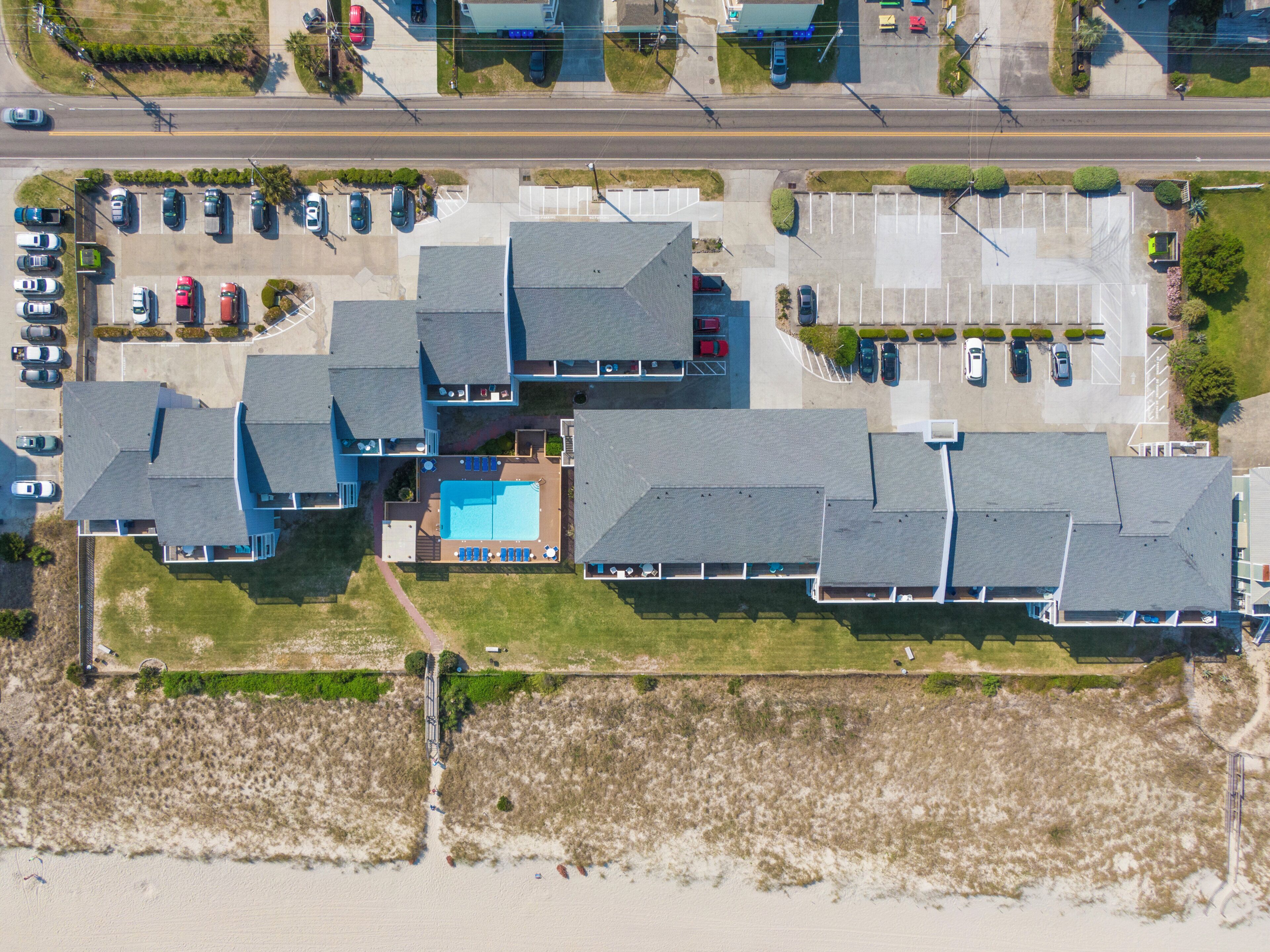 Vue aérienne d’un complexe résidentiel comprenant plusieurs maisons, une piscine et un espace de stationnement.