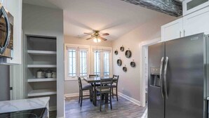 Una cucina moderna con un frigorifero capiente, un tavolo da pranzo in legno e una ventola a soffitto.