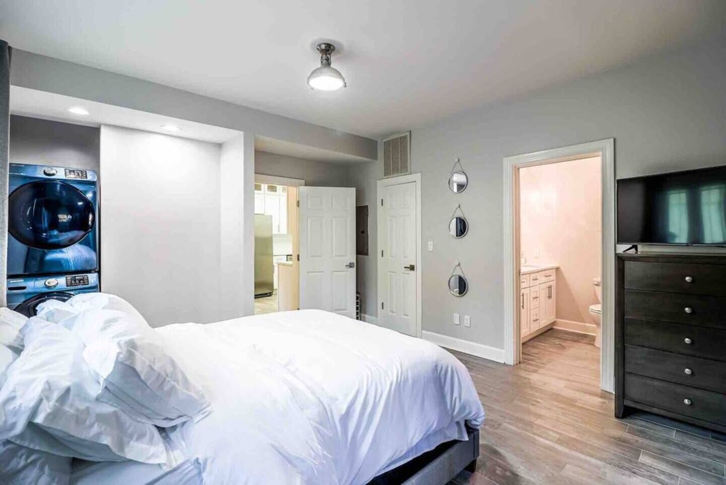 Ein Schlafzimmer mit Bett, Kommode, Spiegel und Deckenleuchte.