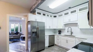Una cucina moderna con mobili bianchi, un frigorifero in acciaio inossidabile e una lavastoviglie.