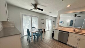 Une cuisine moderne avec un coin repas, de grandes fenêtres et un ventilateur de plafond.