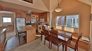 Una cocina amplia con armarios de madera, una isla central y un comedor con sillas.