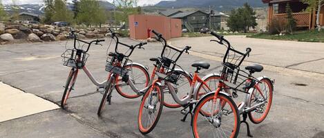 A row of bicycles parked in a lot with a mountain view in the background.