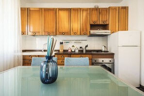 Eine moderne Küche mit Holzschränken, einem Glastisch und einer blauen Vase.