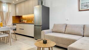 Een moderne keuken met een koelkast, houten kastjes en een eethoek met een tafel en stoelen.