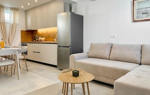 A modern kitchen with a refrigerator, wooden cabinets, and a dining area with a table and chairs. - Beautiful home in Klis (Klis)