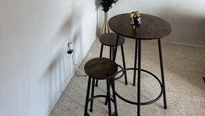 A dining area with a round table, two stools, a vase with plants, a wall-mounted bicycle decoration, and a chandelier. - Gorgeous 1-bedroom condo close to work and play only steps to beach (Satellite Beach)