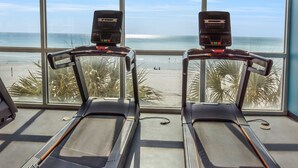Dos cintas de correr en una sala con ventanales que dan a una playa.