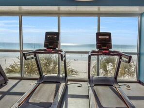 Two treadmills in a room with large windows overlooking a beach. - 2 Gulf front Masters. 1st floor corner unit with wraparound private balcony. (Panama City Beach)