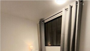 Un lit bien fait, avec une couvre-lit à motifs, une tête de lit et deux oreillers.