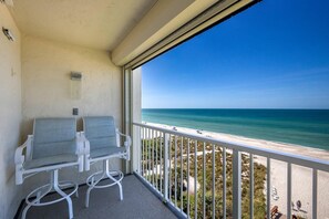 Un balcon avec deux fauteuils en osier blancs et une vue sur la plage.