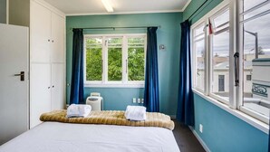 Habitación de hotel con cama, ventana con cortinas, armario y una pequeña mesa con lámpara.