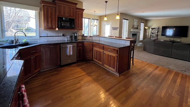 A spacious kitchen with wooden cabinets, a large island, and a built-in microwave. - Spacious 5-bedroom house in Olathe. Finished basement and outdoor deck/space. (Olathe)