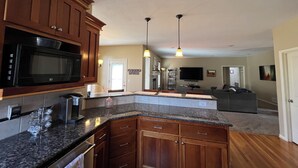 A modern kitchen with granite countertops, wooden cabinets, and a built-in microwave. - Spacious 5-bedroom house in Olathe. Finished basement and outdoor deck/space. (Olathe)