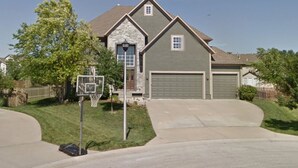 A residential house with a garage, a front yard, and a basketball hoop. - Spacious 5-bedroom house in Olathe. Finished basement and outdoor deck/space. (Olathe)