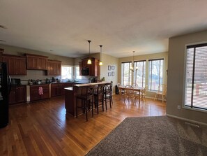 Una cocina amplia con armarios de madera, una isla central y un comedor con sillas.