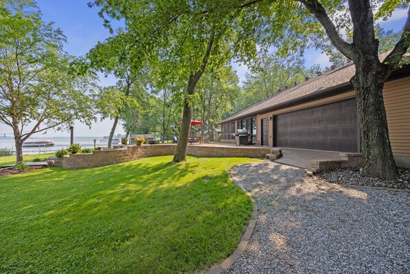 A residential property with a well-maintained lawn, a gravel driveway, and a garage.