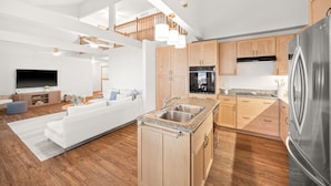 A modern kitchen with wooden cabinets, a stainless steel refrigerator, and a built-in oven.