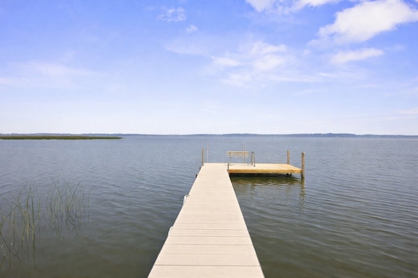 A wooden pier extending into calm water with a clear sky above.