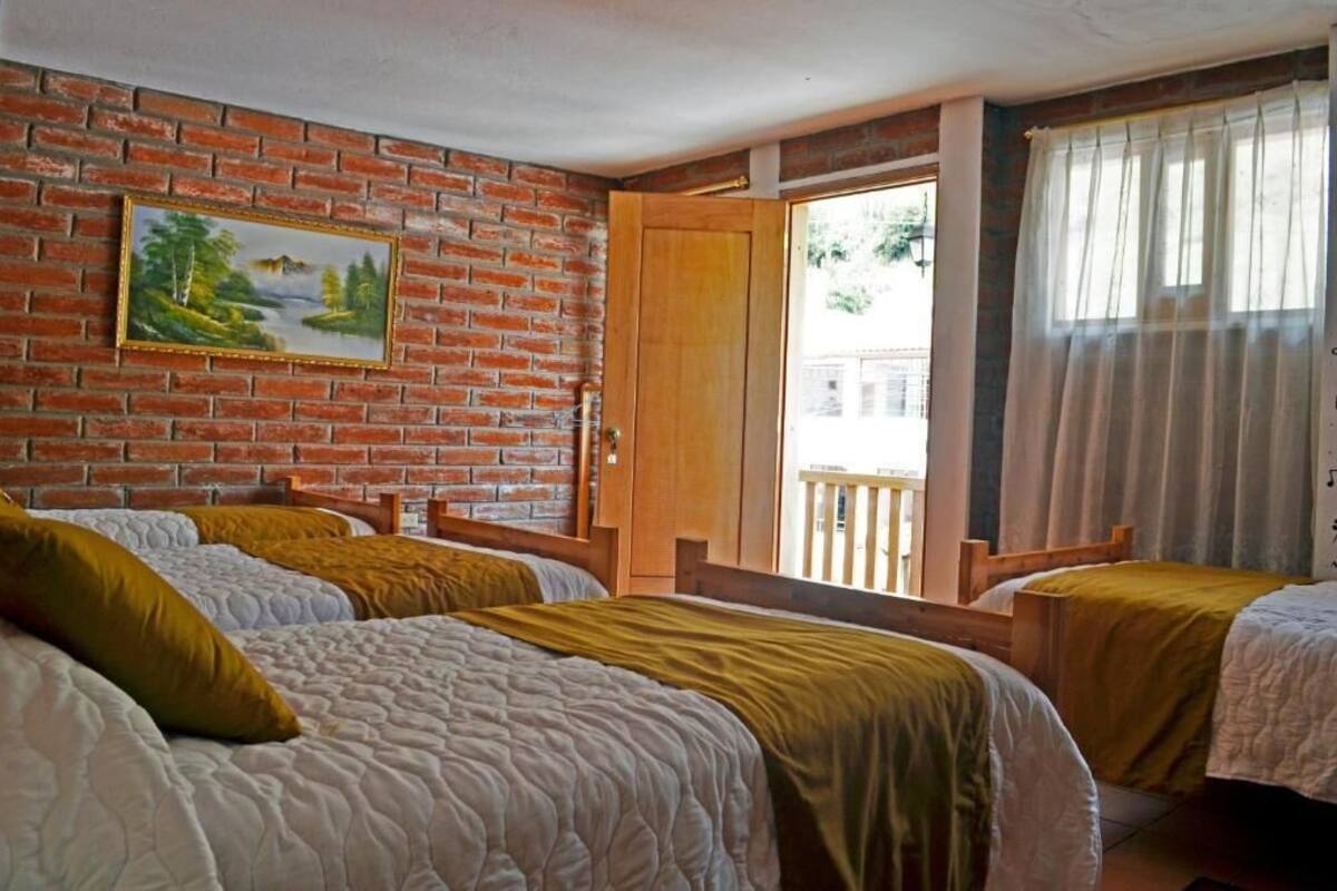 Ein Zimmer mit zwei Betten, einer Ziegelwand, einem Gemälde und einem Balkon mit Blick.