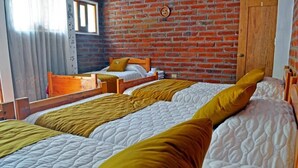 A room with two beds, a brick wall, and a wooden door. - LAGOON HOTEL (Chugchilan)