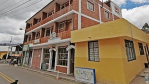 A two-story hotel with a brick facade and a yellow corner building. - LAGOON HOTEL (Chugchilan)