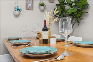 A dining table set with turquoise plates, wine glasses, and a bottle of wine. - Chimney Park Retreat King Suite + Fenced Yard (Windsor)