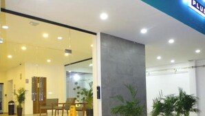 Entrada d'hotel amb una porta de vidre, una escala que puja i una zona de recepció visible a l'interior.