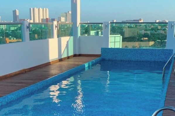 Une piscine sur le toit, avec une terrasse en bois et une vue sur la ville.