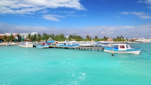 A marina with several boats docked, a pier extending into the water, and a building with a red roof in the background. - Relax in 2 Stylish Rooms with Rooftop Sun Terrace in Central Cancún Location (Cancún)