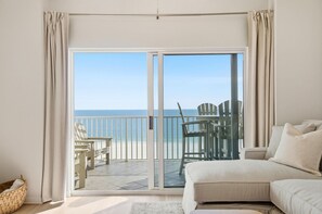 A room with a sliding glass door leading to a balcony with beach chairs and a table. - Tidewater 804 (Orange Beach)