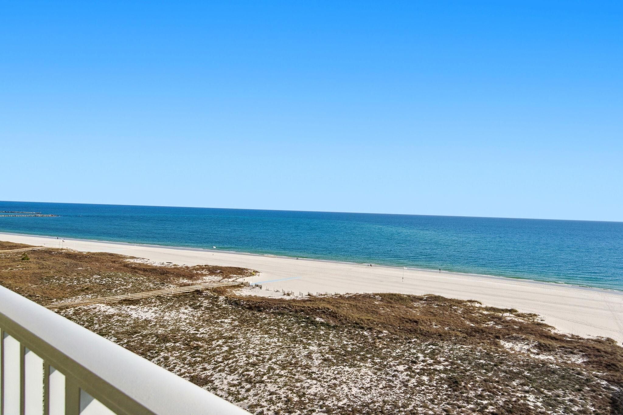 A beach view from a balcony with a clear sky.
