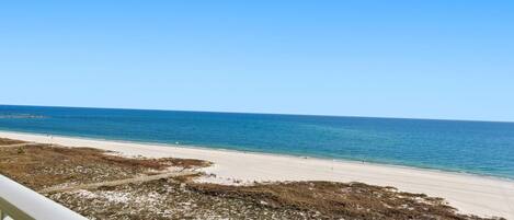 A beach view from a balcony with a clear sky.