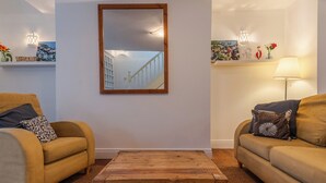 Ein Wohnzimmer mit zwei Sofas, einem Couchtisch, einem Spiegel und dekorativen Gegenständen auf Regalen.