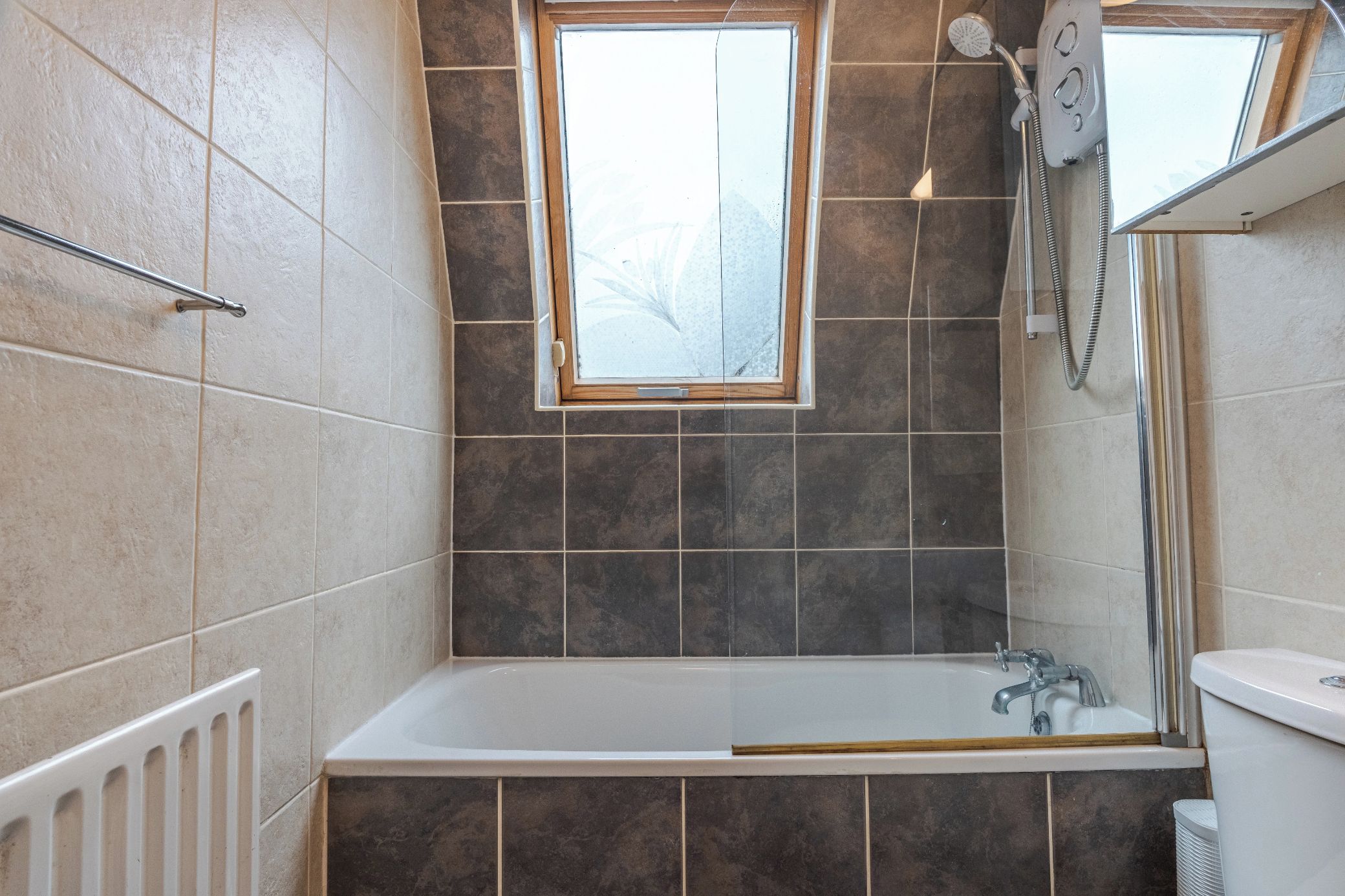 A bathroom with a bathtub, a shower, and a window.