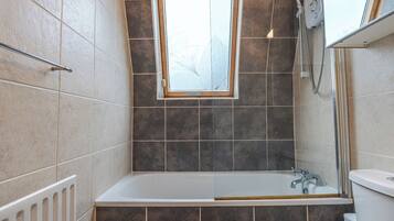 A bathroom with a bathtub, a shower, and a window.