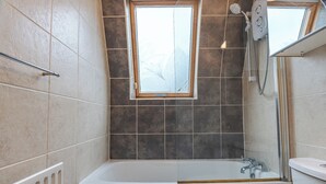 Ein Badezimmer mit einer Badewanne, einer Dusche und einem Fenster.
