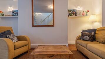 A living room with two sofas, a coffee table, a mirror, and decorative items on shelves.