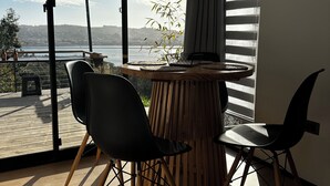 A modern room with a large window, a round wooden table, two black chairs, and a bamboo plant. - pro estancia 1 (constitución)
