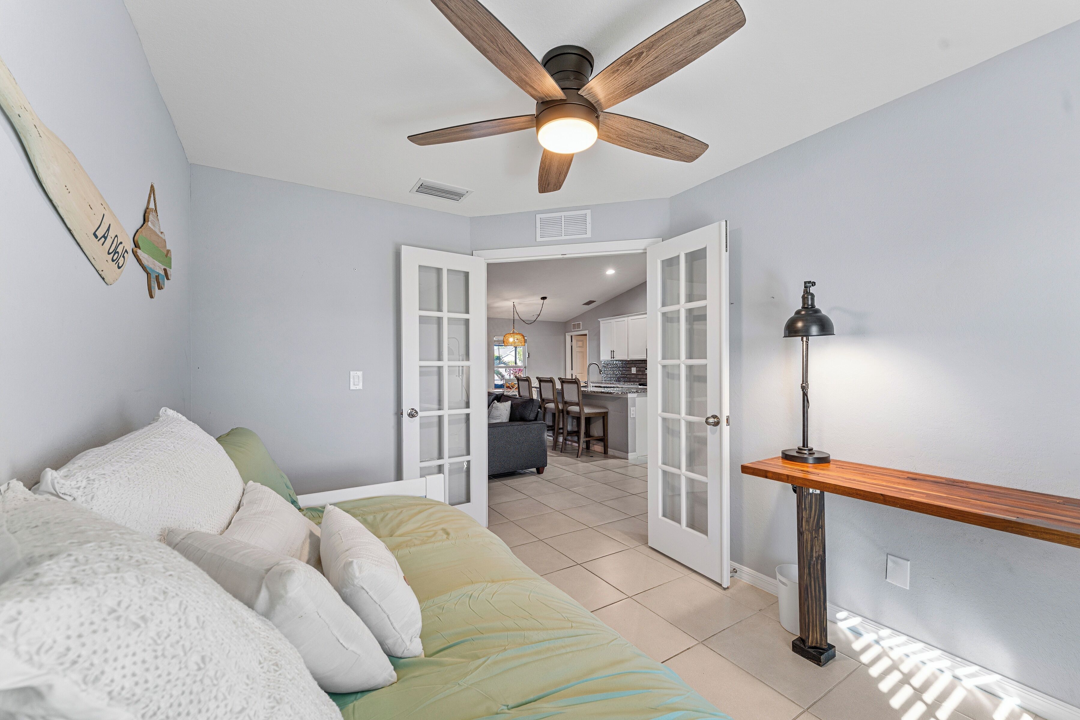 A bedroom with a bed, a ceiling fan, and a view into the living area.