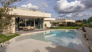 A modern house with a swimming pool, outdoor furniture, and a well-maintained garden. - Lagoon Residence 56 Deluxe - Premium Accommodation (Óbidos)