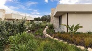A modern building with a stone facade, a stone pathway, and various plants. - Lagoon Residence 56 Deluxe - Premium Accommodation (Óbidos)