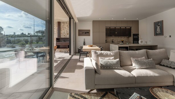 A modern living room with a large sofa, a dining area, and a kitchen. - Lagoon Residence 56 Deluxe - Premium Accommodation (Óbidos)