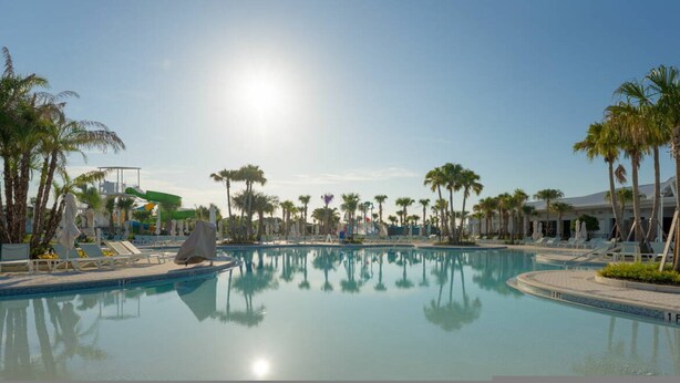 A pool with clear water, surrounded by palm trees and lounge chairs. - 7BR Windsor Cay w Game Room Pool Near Disney (Clermont)