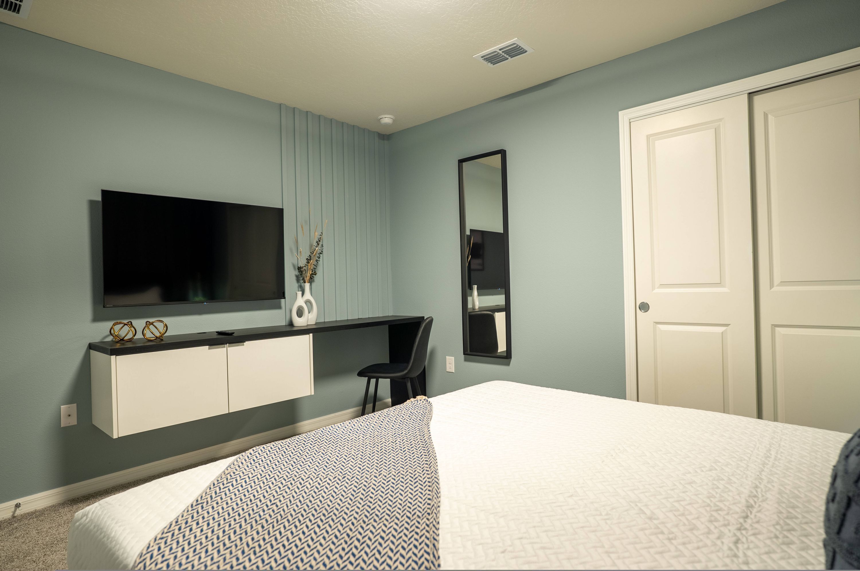 Une chambre à coucher avec un lit, une télévision, un bureau et une armoire.