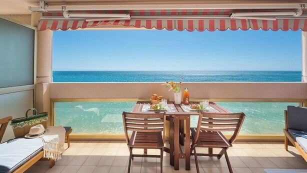 Ein Balkon mit Tisch für zwei Personen, mit Blick auf das klare, blaue Meer.