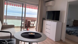 Ein Hotelzimmer mit Balkon, Fernseher, Bett und einer Essecke mit Tisch und Stühlen.