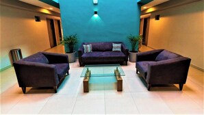 A modern lobby with a blue accent wall, two sofas, a coffee table, and potted plants. - Spacious Coastal Nook with Poolside Serenity Near the Boardwalk (Mazatlán)
