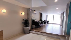 A modern hotel lobby with a reception desk, seating area, and large windows. - Sun & Sea Getaway Offering Comfort, Convenience & Beachside Charm (Mazatlán)